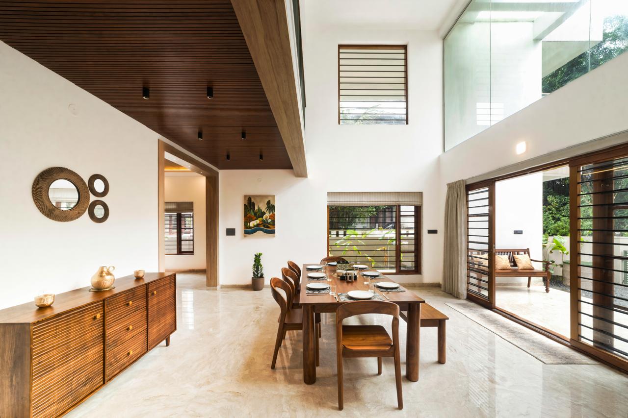 Double-height dining with slatted timber ceiling and teak sideboard — Interior work by Alpha Design Studio