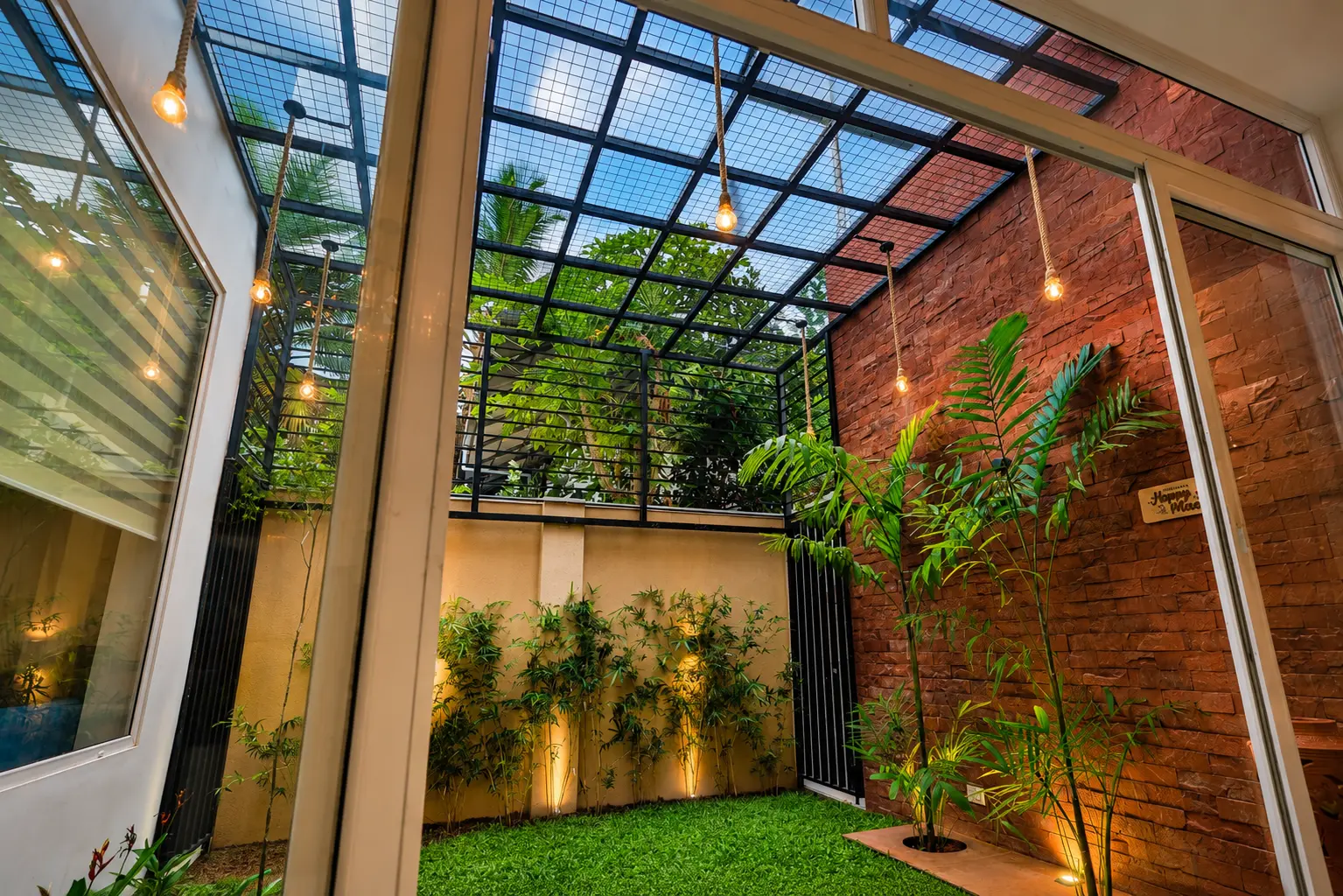 Glass-roofed courtyard with brick wall and green lawn — Interior work by Alpha Design Studio